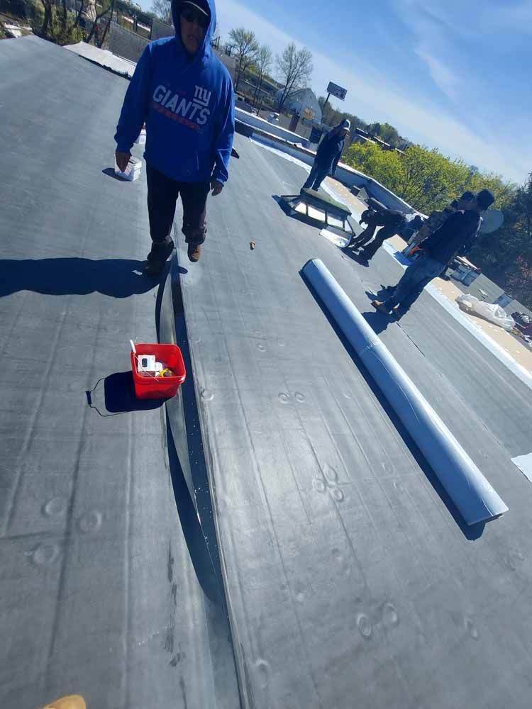 A man wearing a giants sweatshirt is standing on a roof