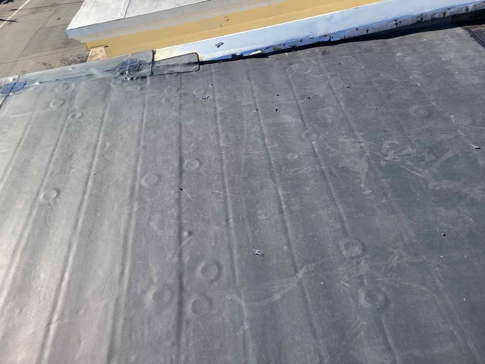 A close up of a black roof with holes in it.