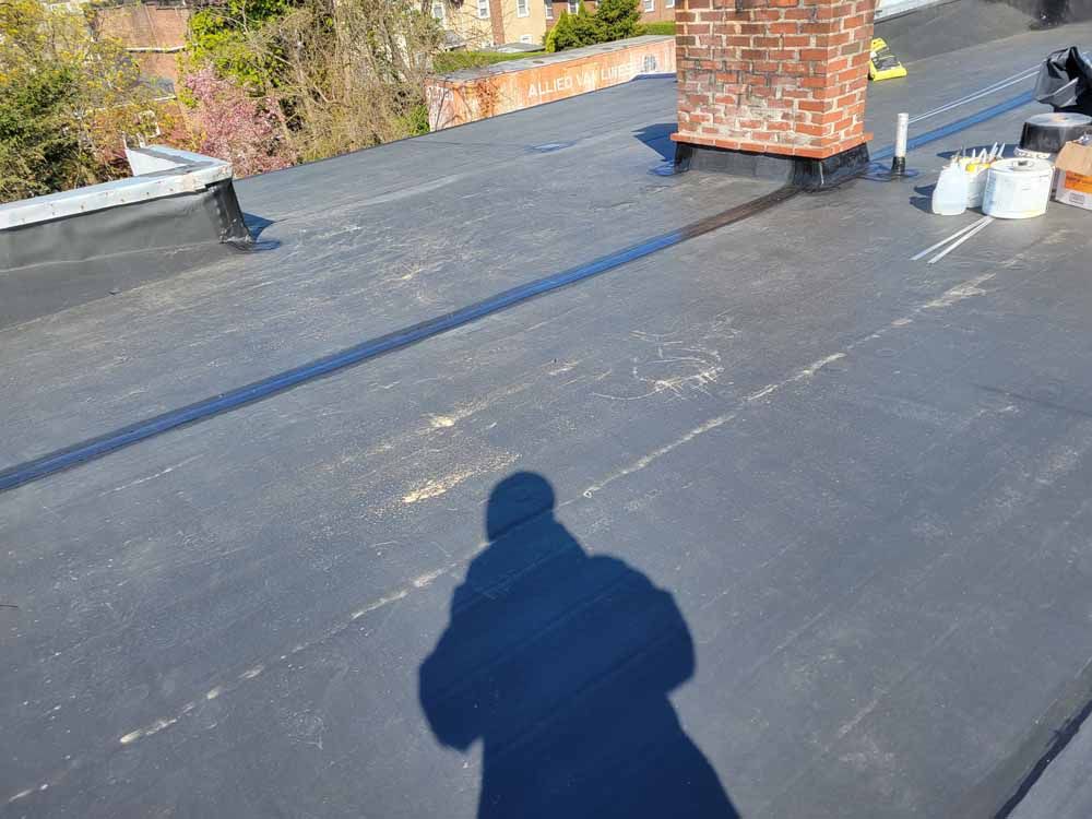 A shadow of a person is cast on the roof of a building.