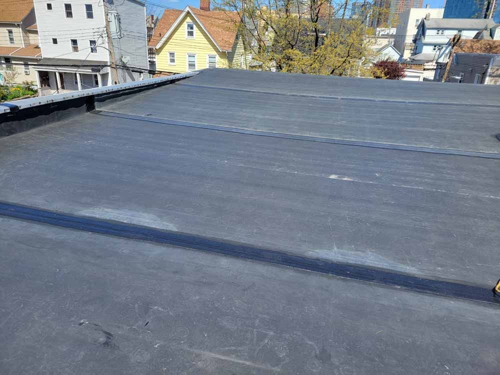 A black roof with a lot of houses in the background.