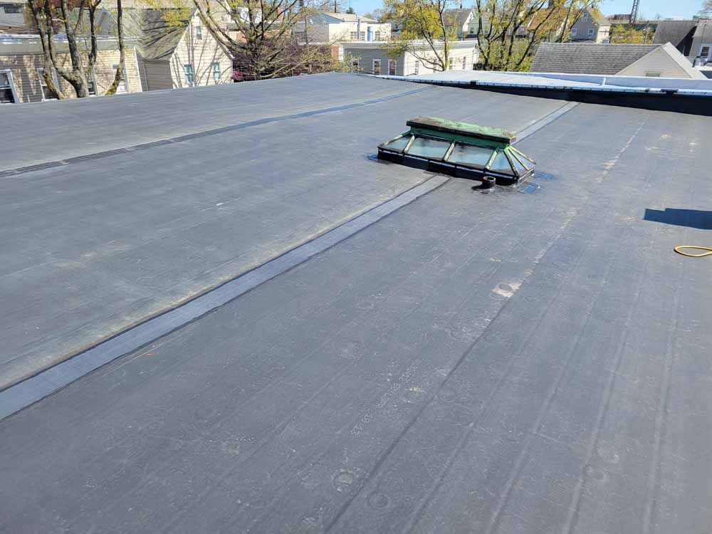 A black roof with a green vent on top of it.