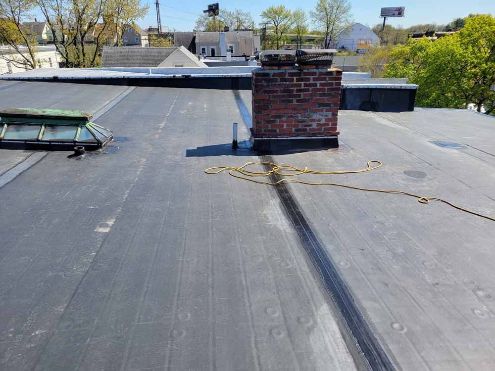 A black roof with a brick chimney on top of it.