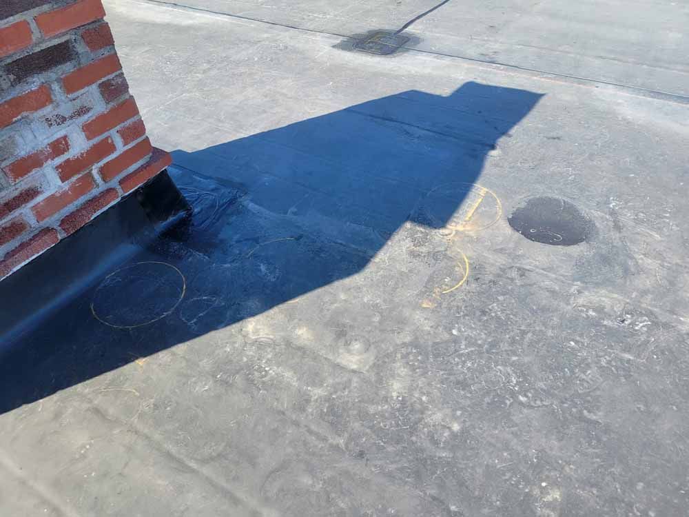 A shadow of a brick chimney is cast on the ground