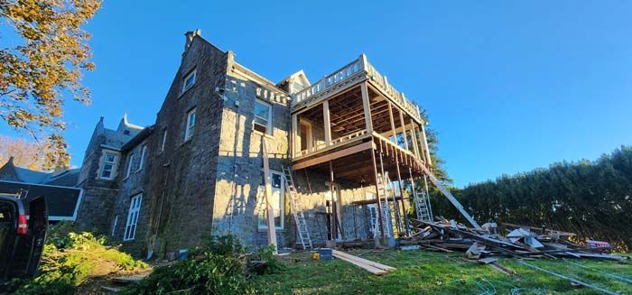 A large brick house is being remodeled with a wooden deck.