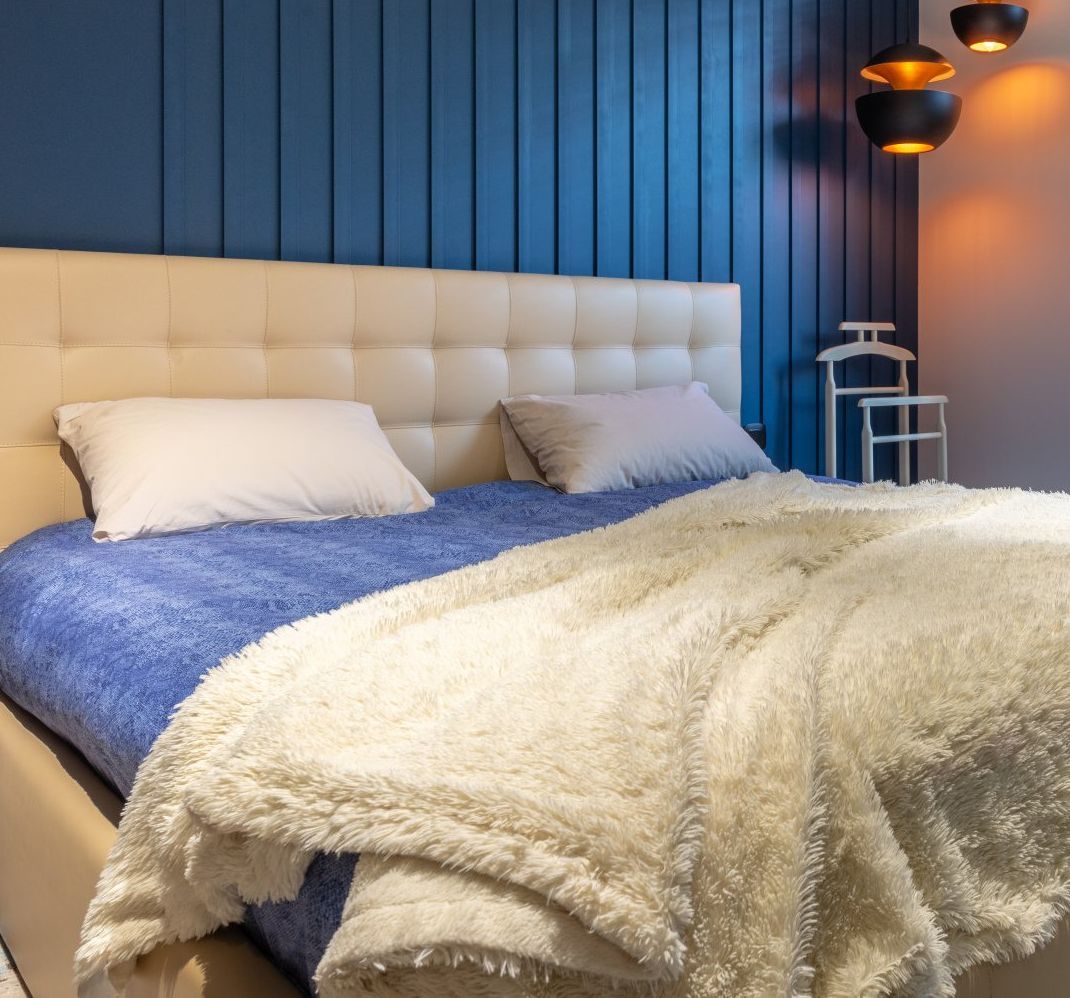 A bed with a blue blanket and a white blanket on it