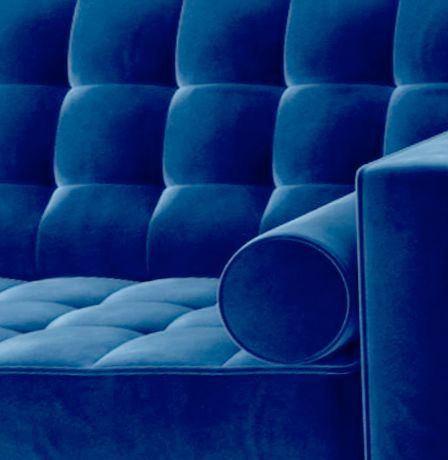 A close up of a blue couch with a round arm rest