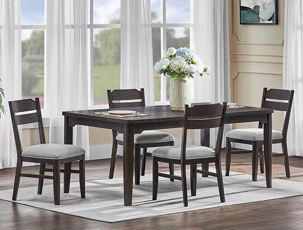 Dark wood dining table with six chairs in a bright room by large windows and a vase of flowers