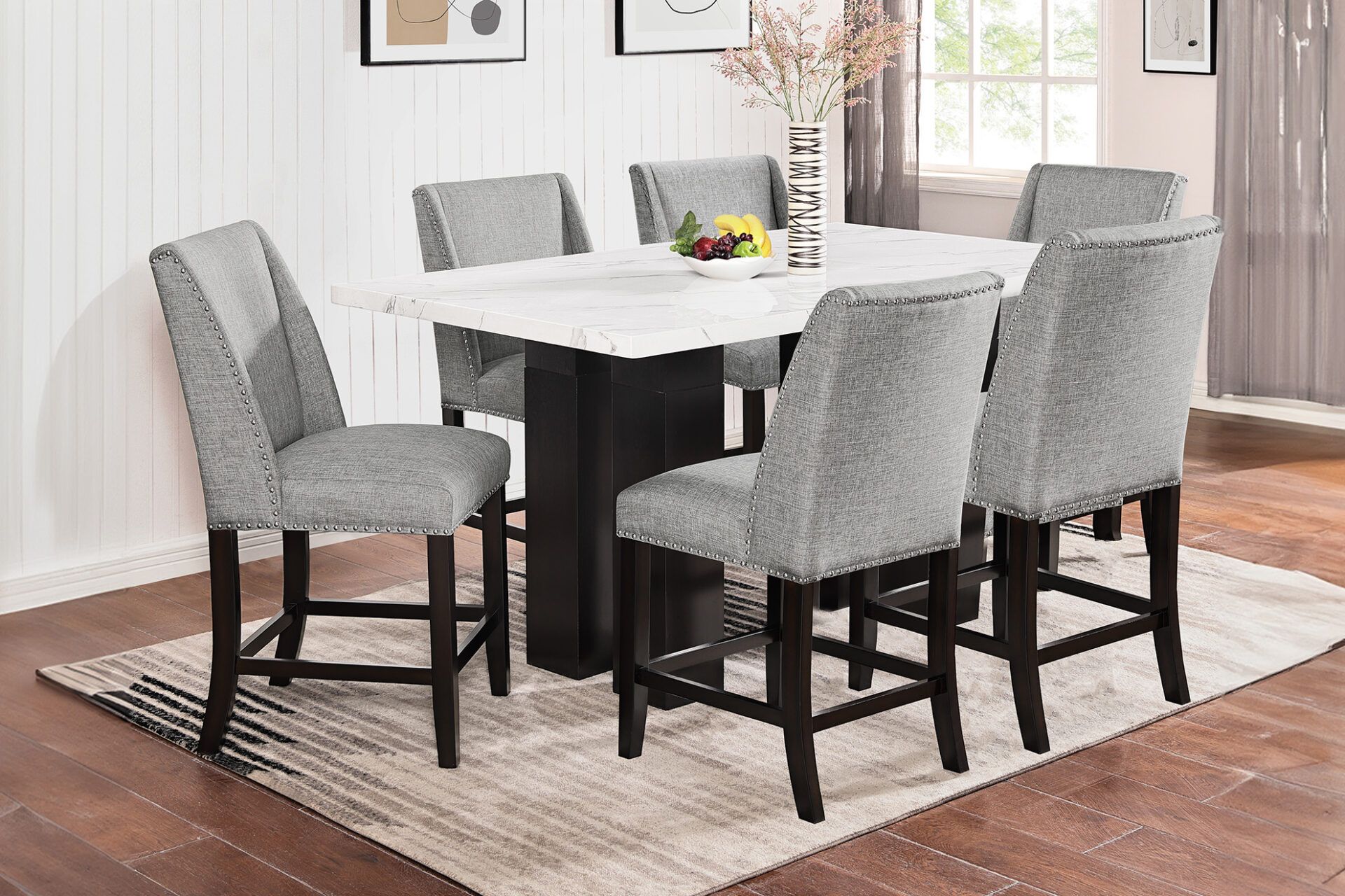 Modern dining table with six gray upholstered chairs on a light rug in a bright room