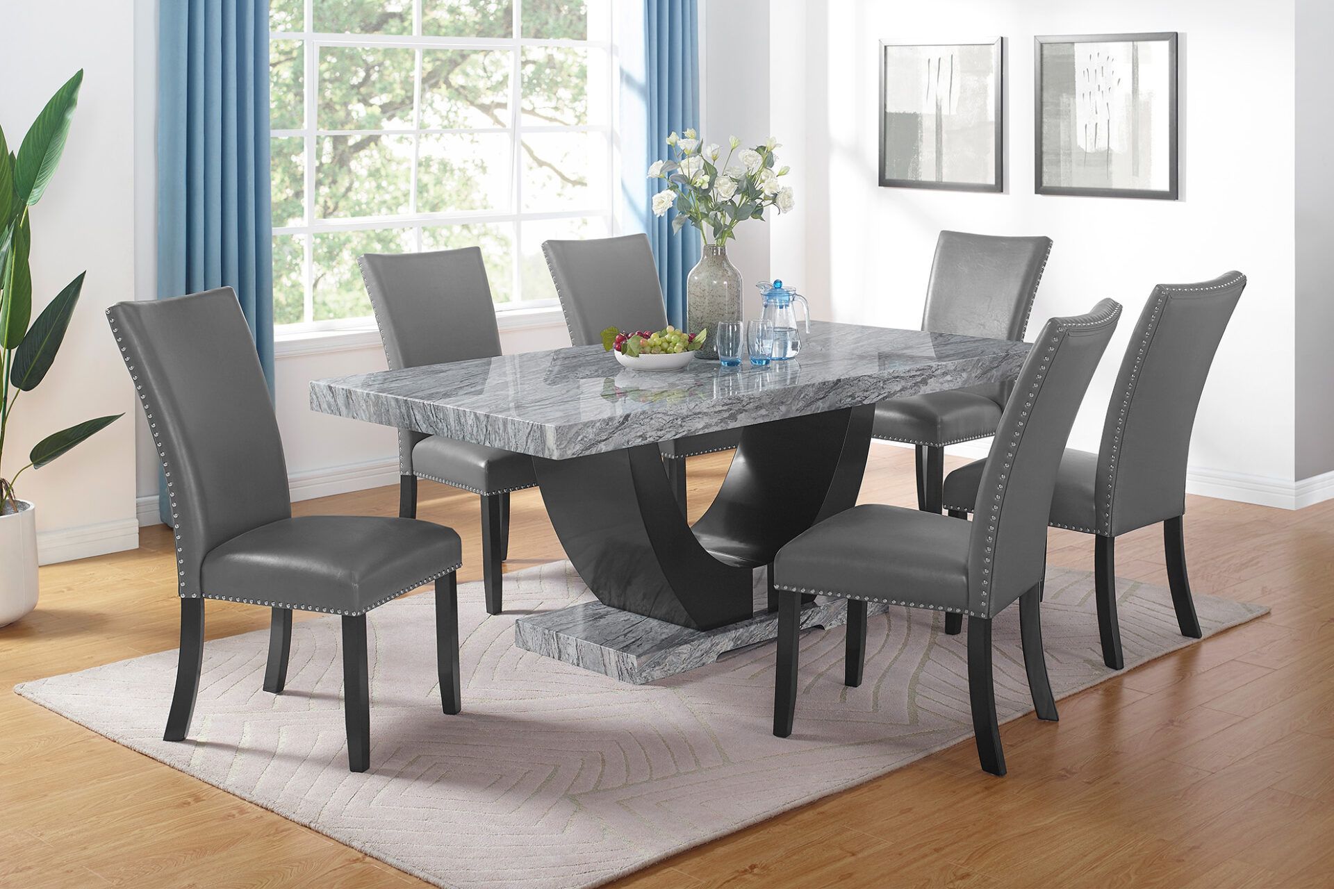 Modern dining room with a glass table, six gray chairs, and a window with blue curtains