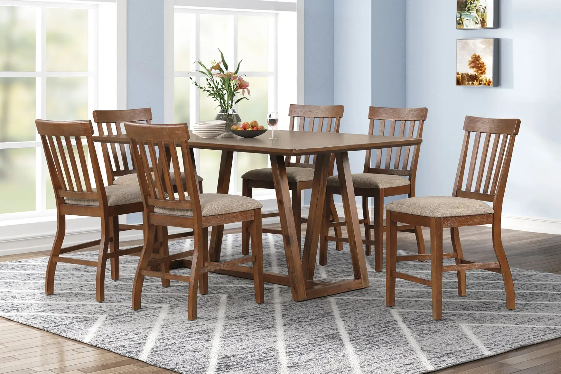Wooden dining table and six chairs in a bright room with large windows and a patterned rug