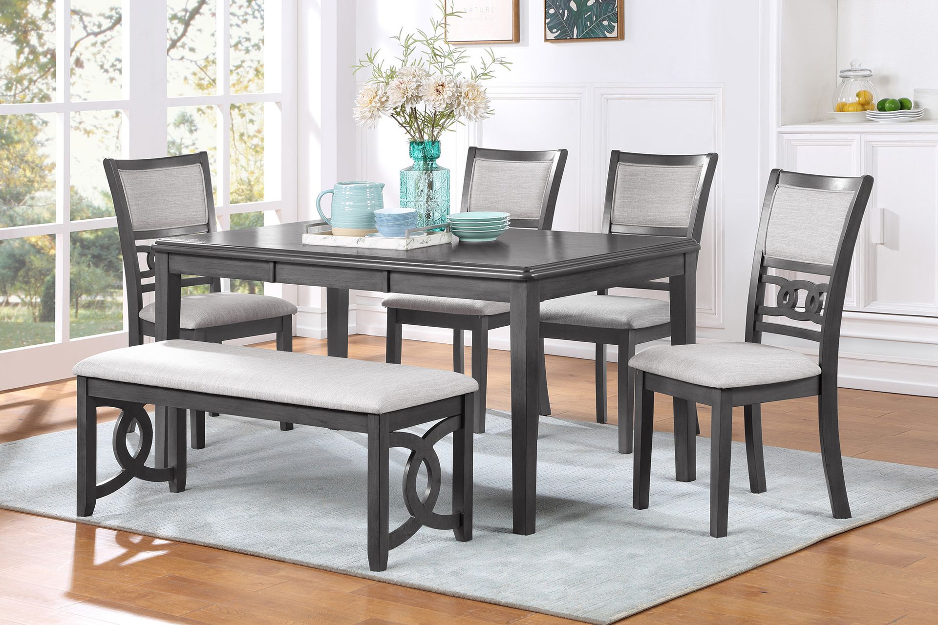 Gray dining set with glass table, four chairs, and bench in a bright room