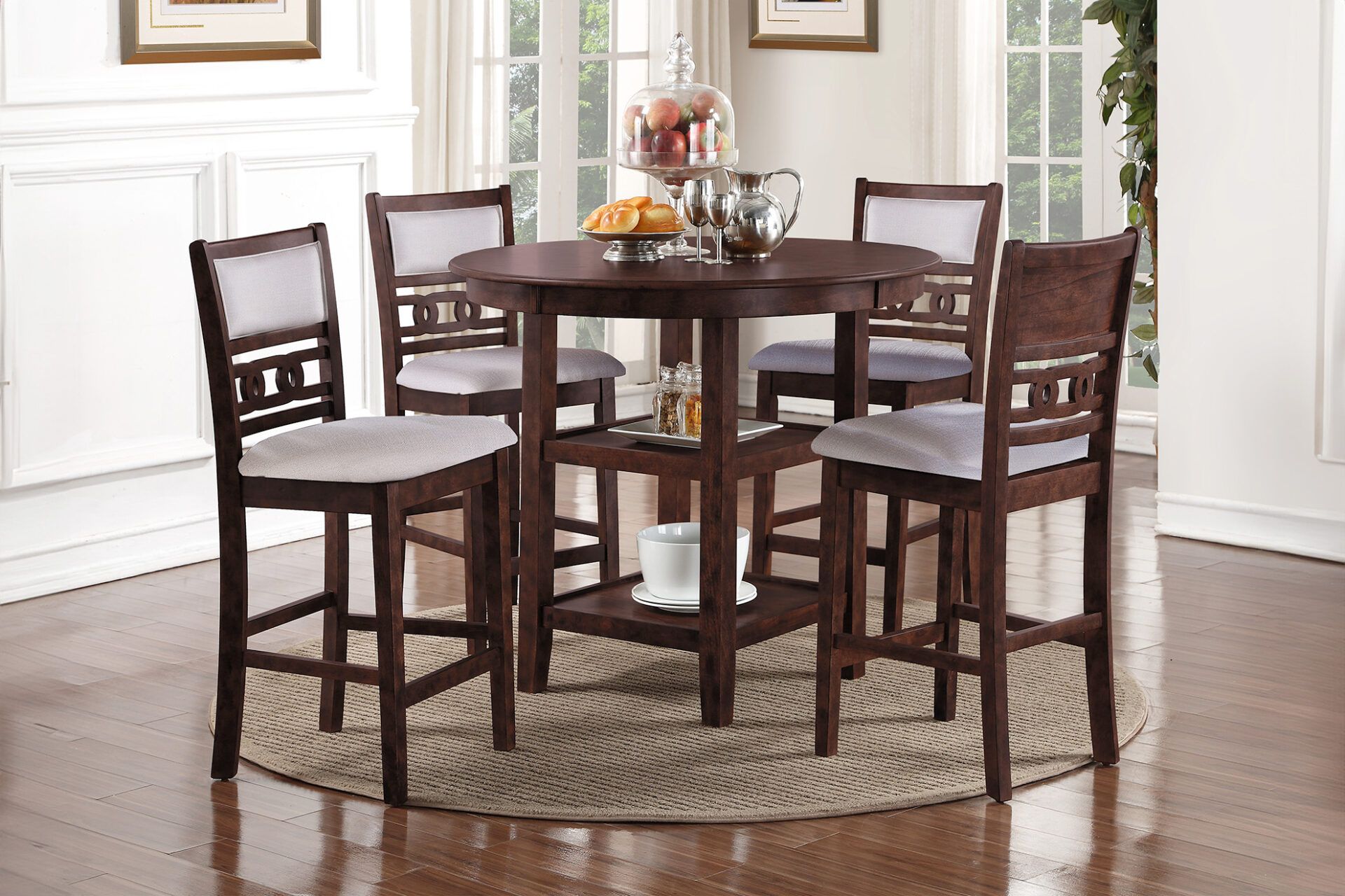Dark wood dining table set with four chairs on a round rug in a bright room