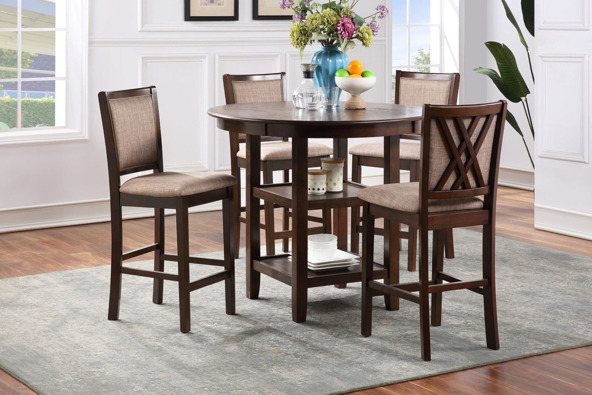 Dining table set with four dark wooden chairs in a bright room with windows and a rug.