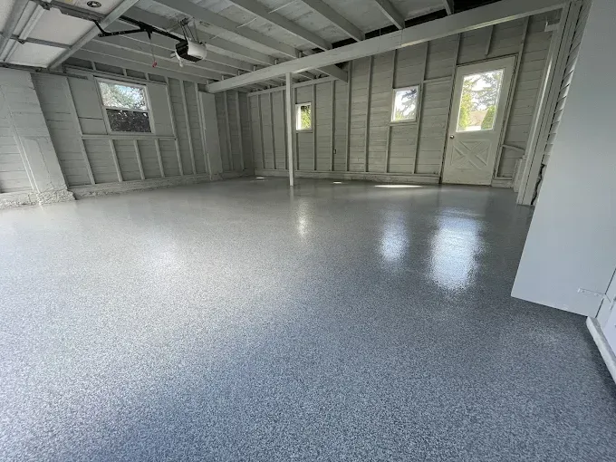 Empty garage with gray epoxy floor, open door.