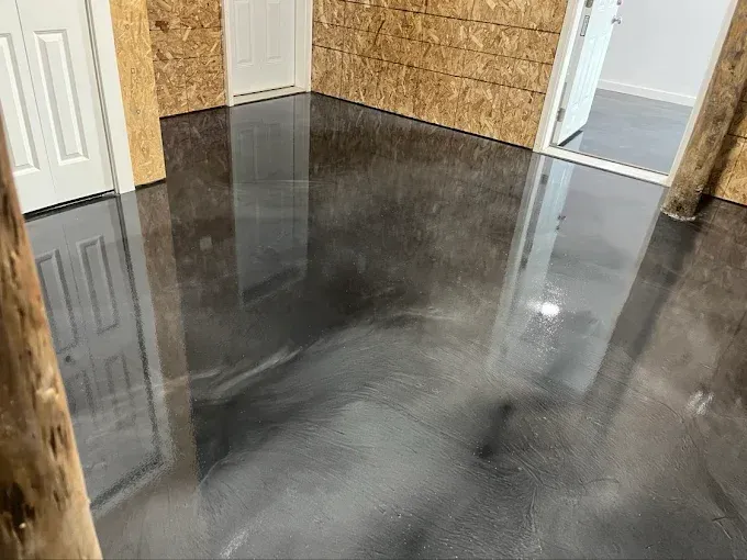 Shiny metallic gray epoxy floor in a room with wood walls and two white doors.