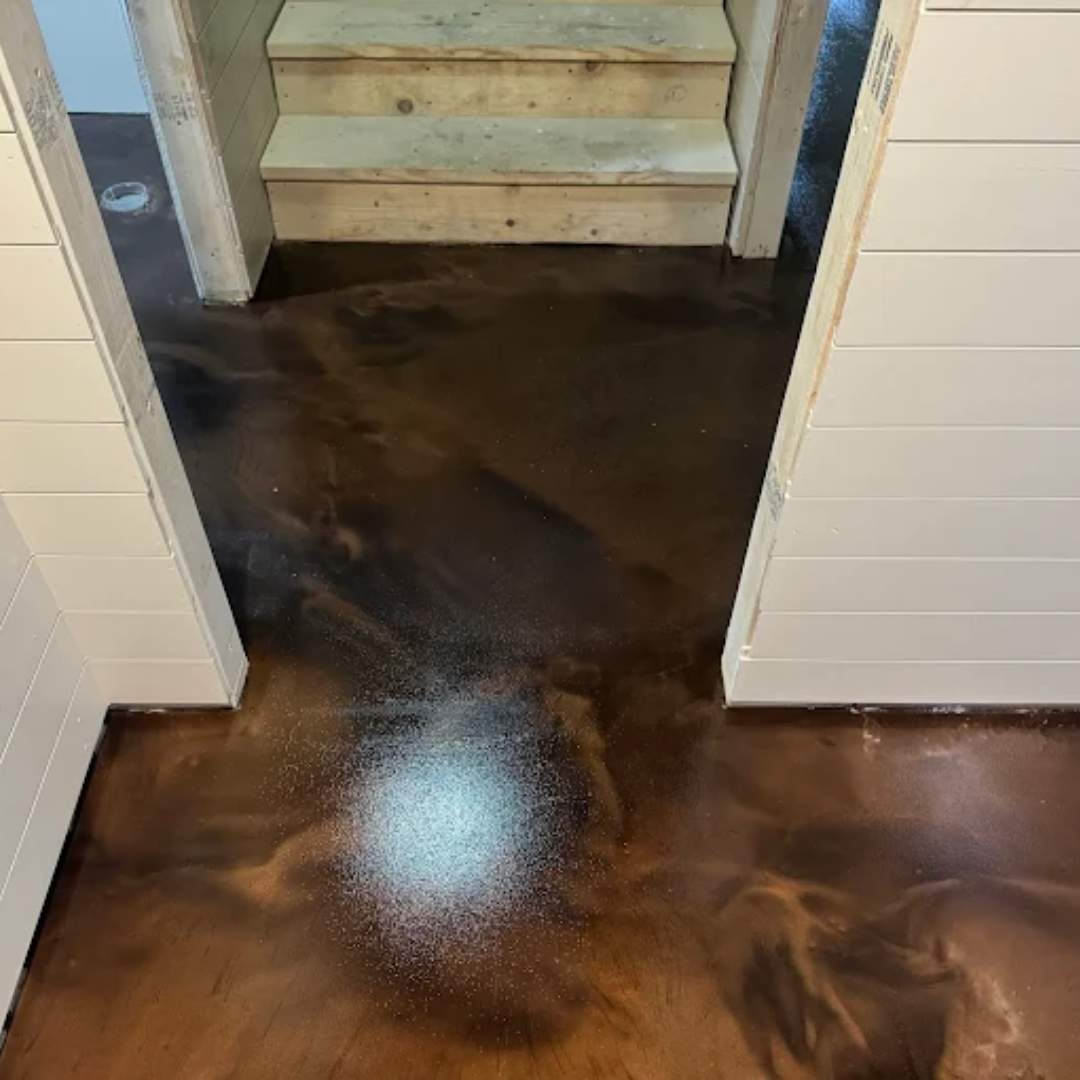 A brown metallic epoxy floor with stairs in the background, framed by white walls.