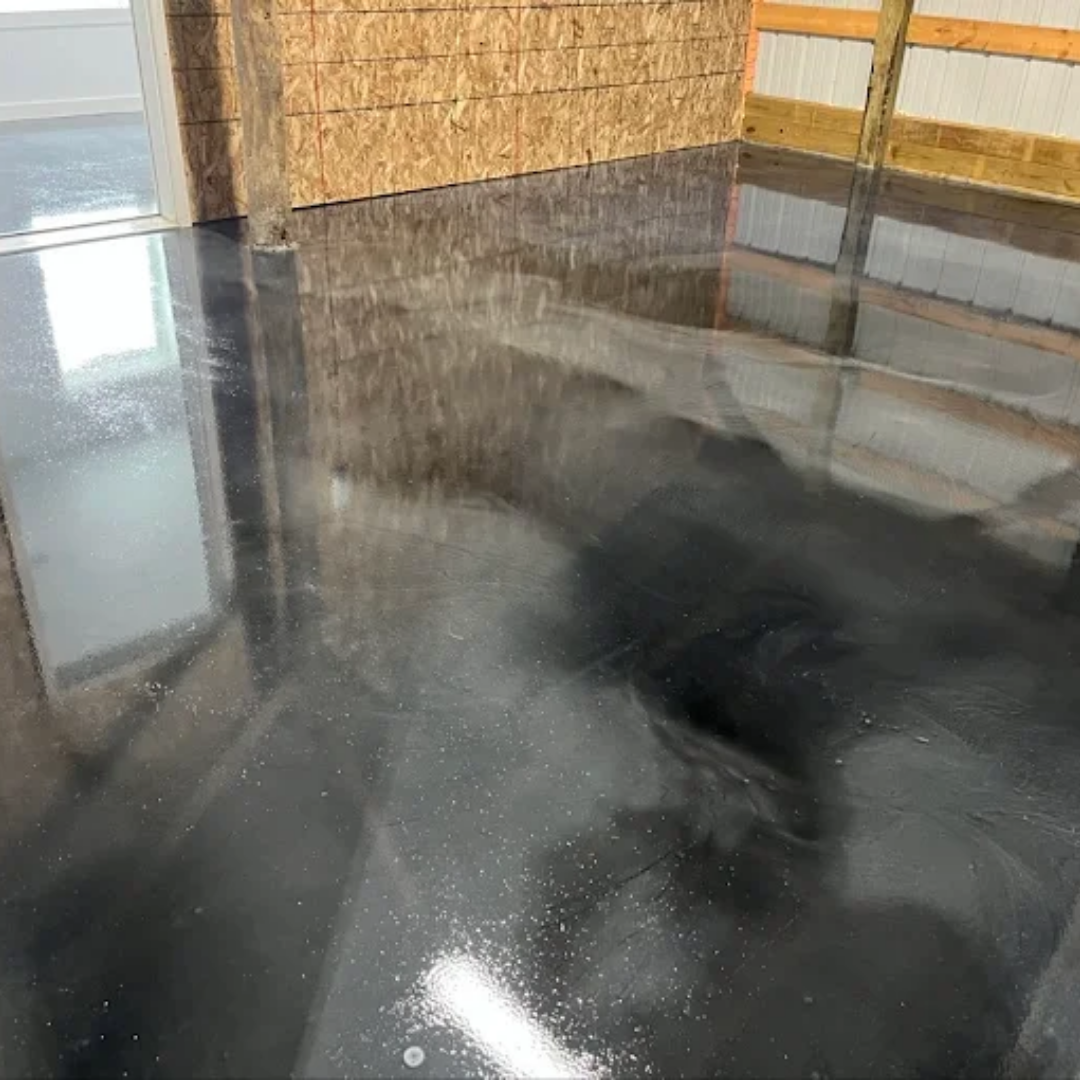 Glossy black and gray epoxy floor reflecting light, in an industrial setting.