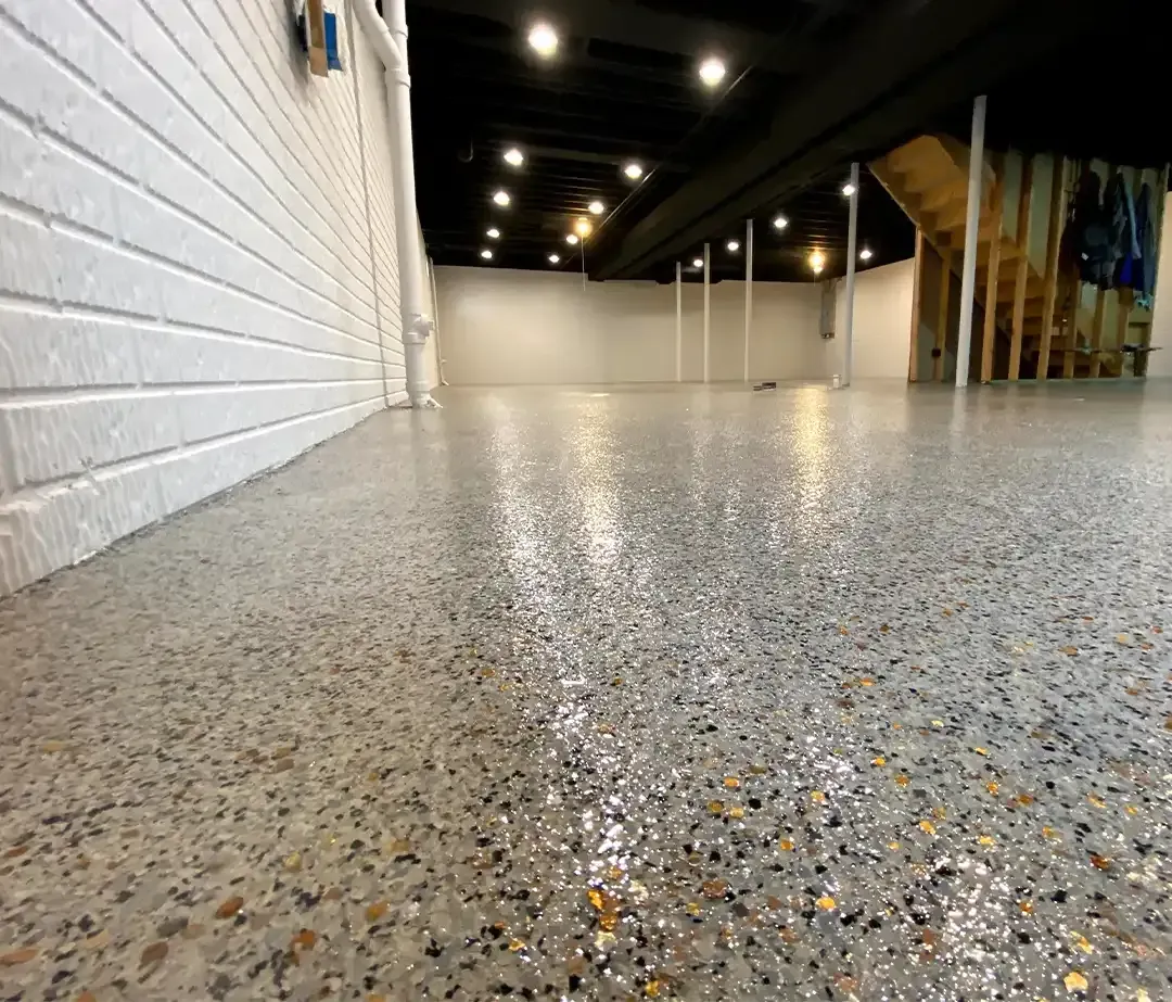 Person pouring yellow epoxy from a bucket onto a concrete floor.