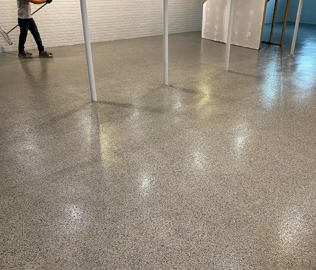 Room under construction with a polished, speckled floor; unfinished walls and ceiling; French doors.