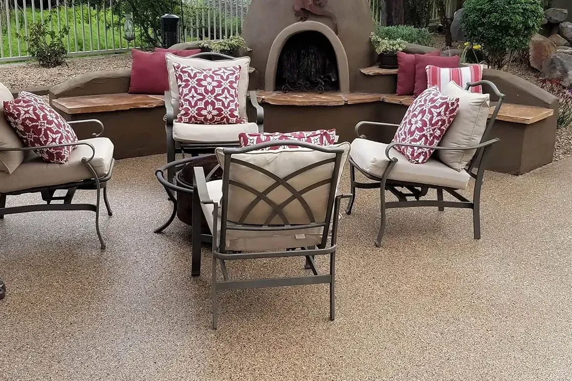Patio with seating around a fire pit and a built-in fireplace, cushions in red and white.