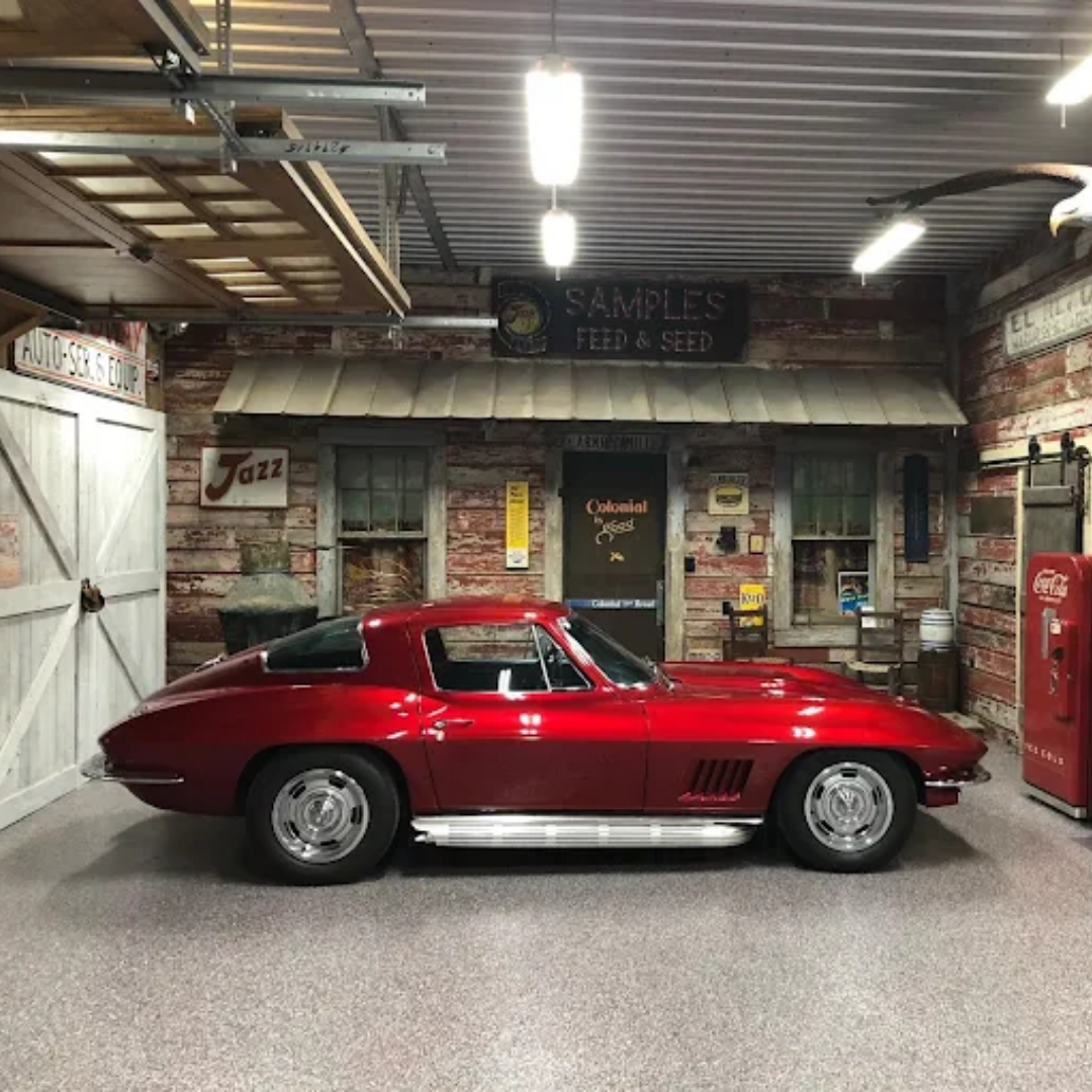 Red classic car in a garage with a vintage-themed facade.