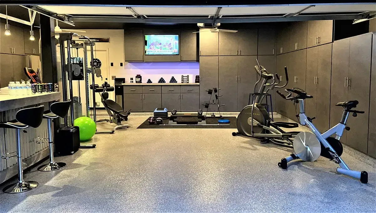 Home gym with exercise equipment, bar, and storage cabinets.