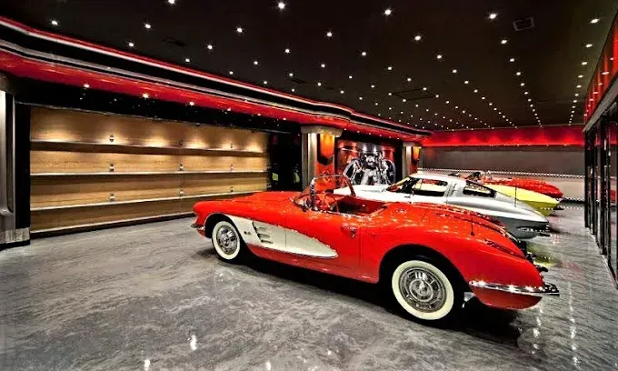 Red Corvette in a luxury garage with other classic cars.