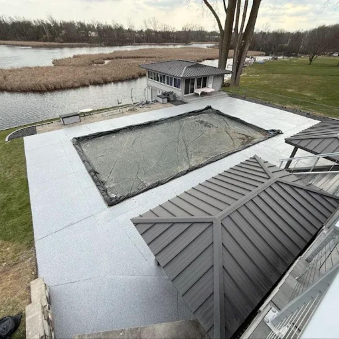 Overhead view: Pool area with covered pool, gazebo, lake in background, overcast day.