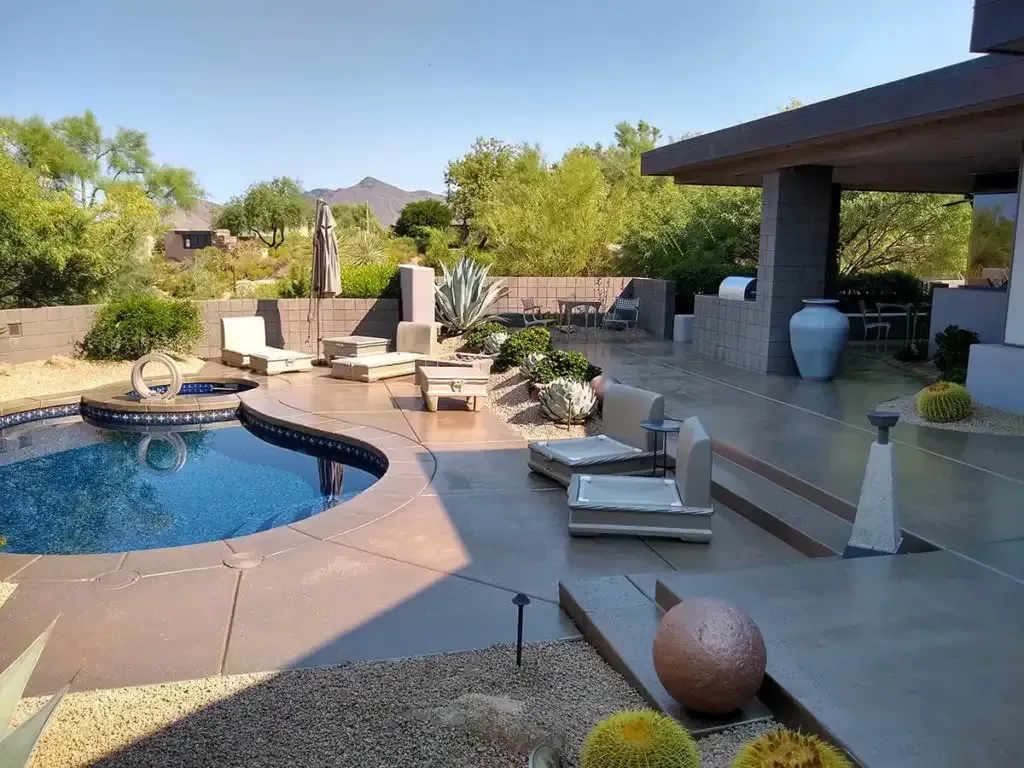 Patio with pool, lounge chairs, and desert landscaping under a sunny sky.