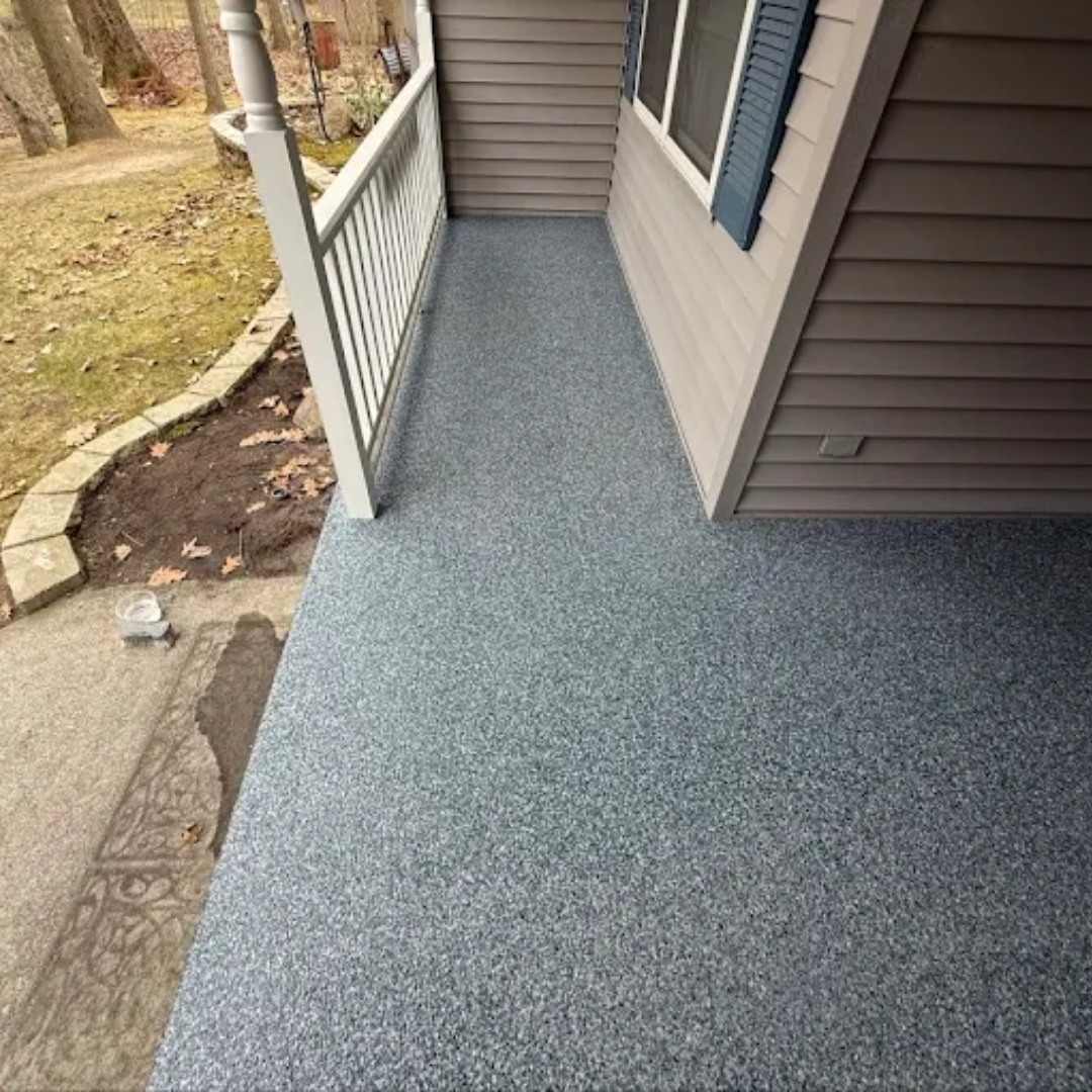 Gray speckled porch floor with a handrail, next to a gray siding wall.