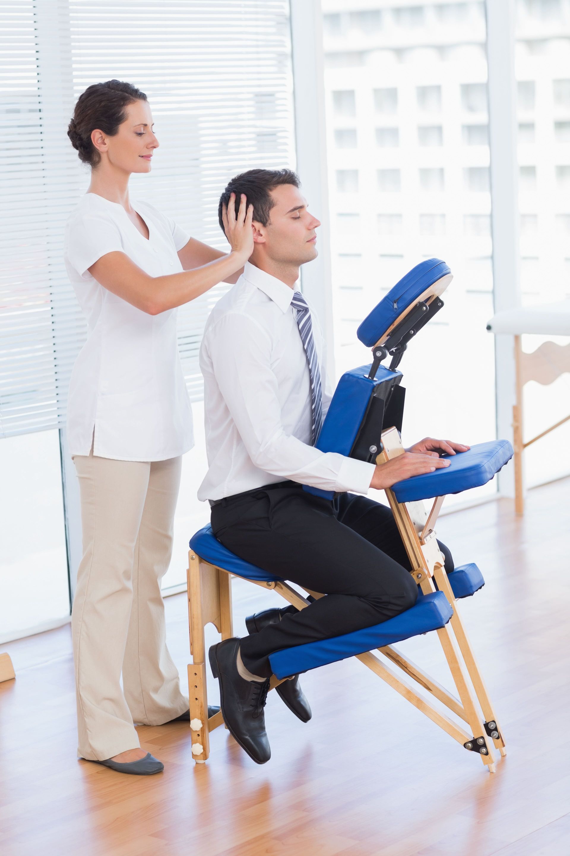 a man sits in a chair while the massage therapist massages his head