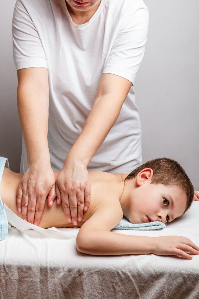 young boy massage Boy Lying On Bed While Receiving Foot Massage From Young ...