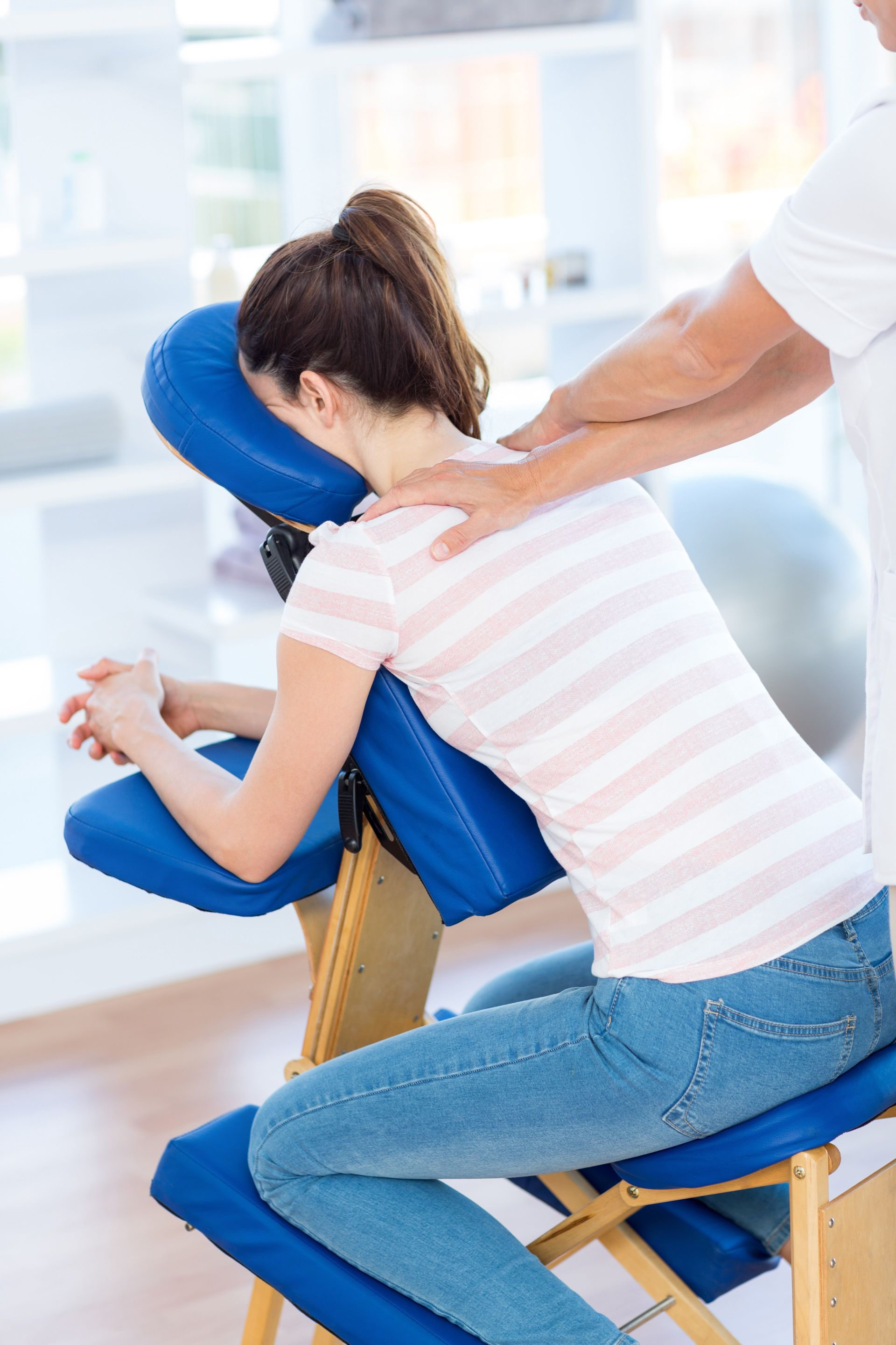 a woman is sitting in a chair receiving a massage treatment