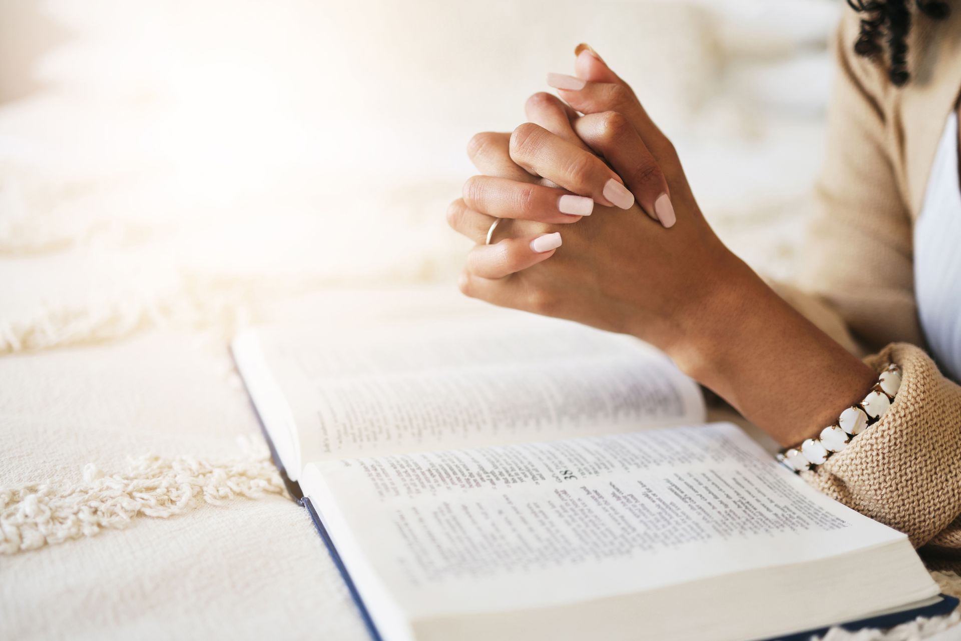 Side view of woman praying with wooden cross and bible