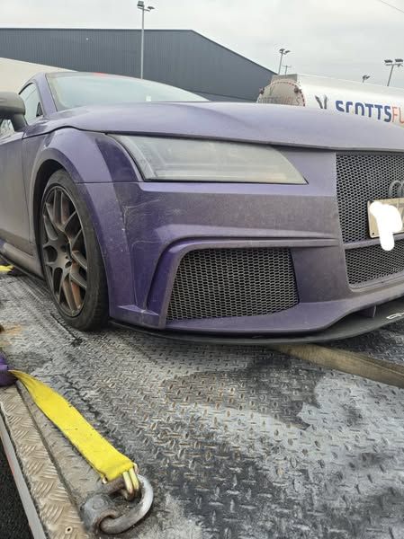 A purple car is sitting on top of a tow truck.