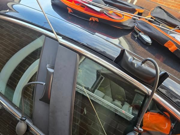 A black car is parked in front of a brick house