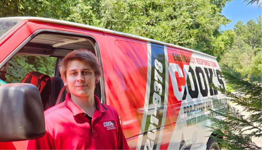 A man in a red shirt is standing in front of a red van.