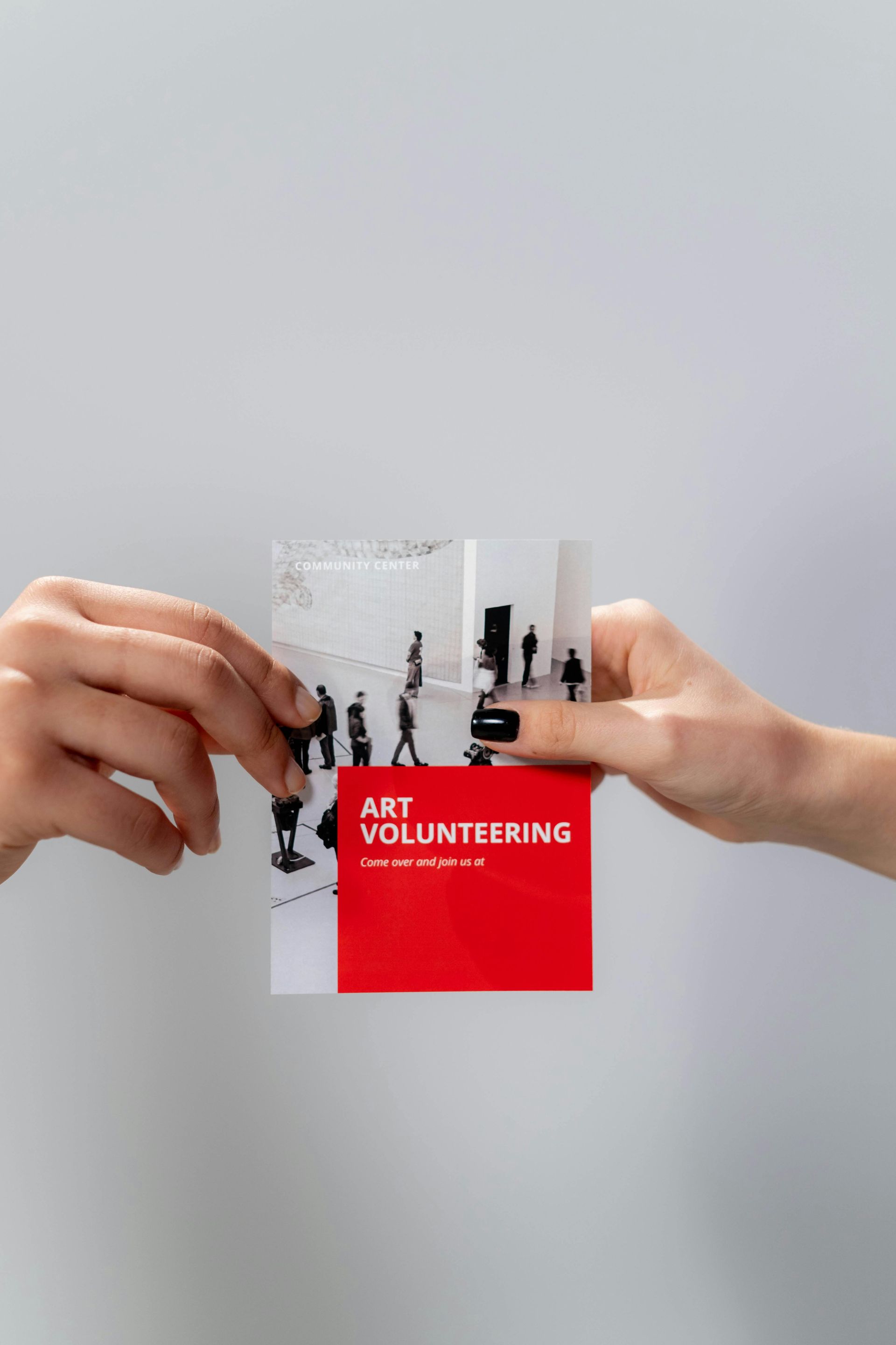 Two people are holding a brochure for art volunteering.