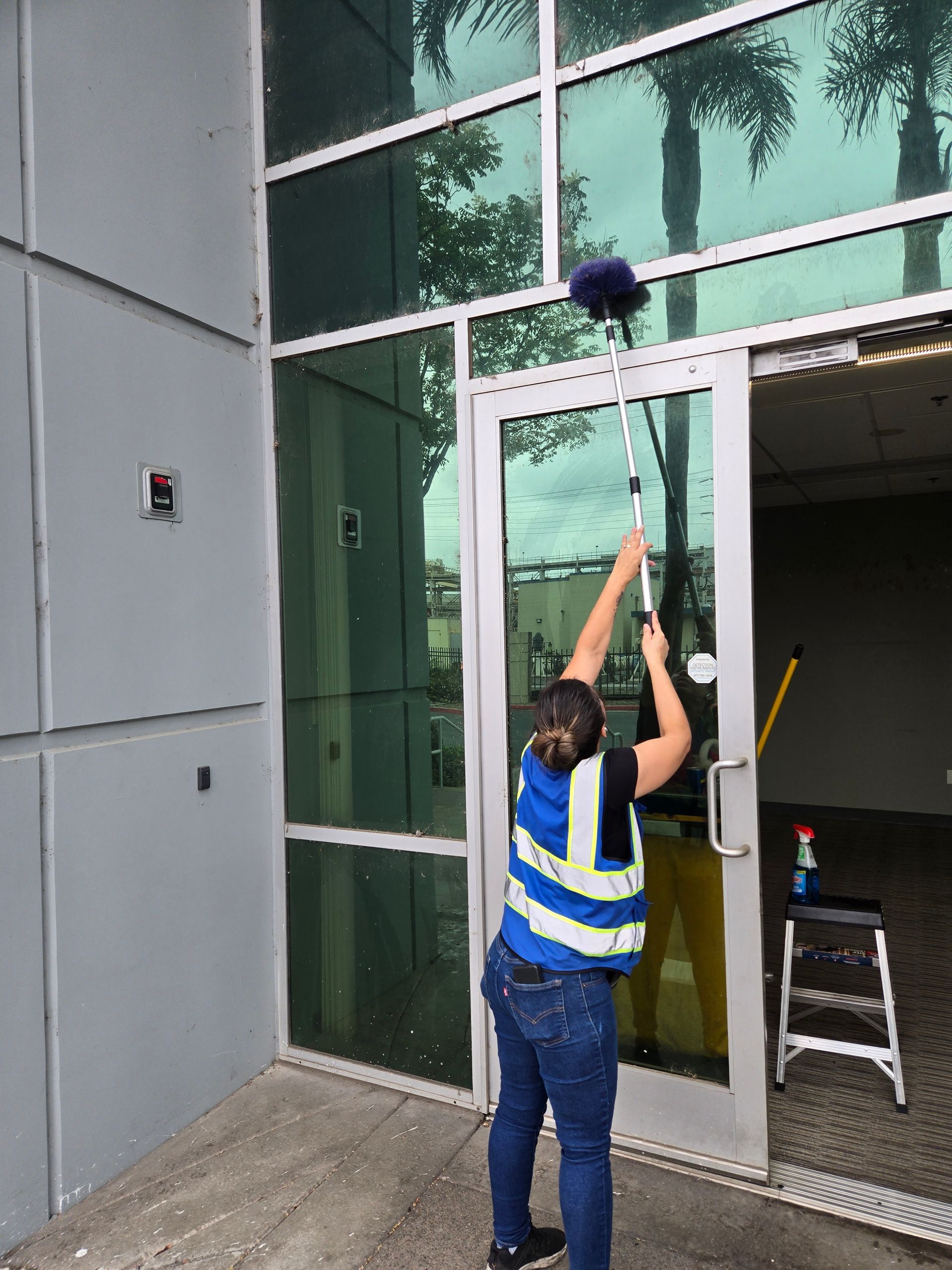 Hands in orange gloves cleaning a bathroom sink with a spray bottle and cloth.