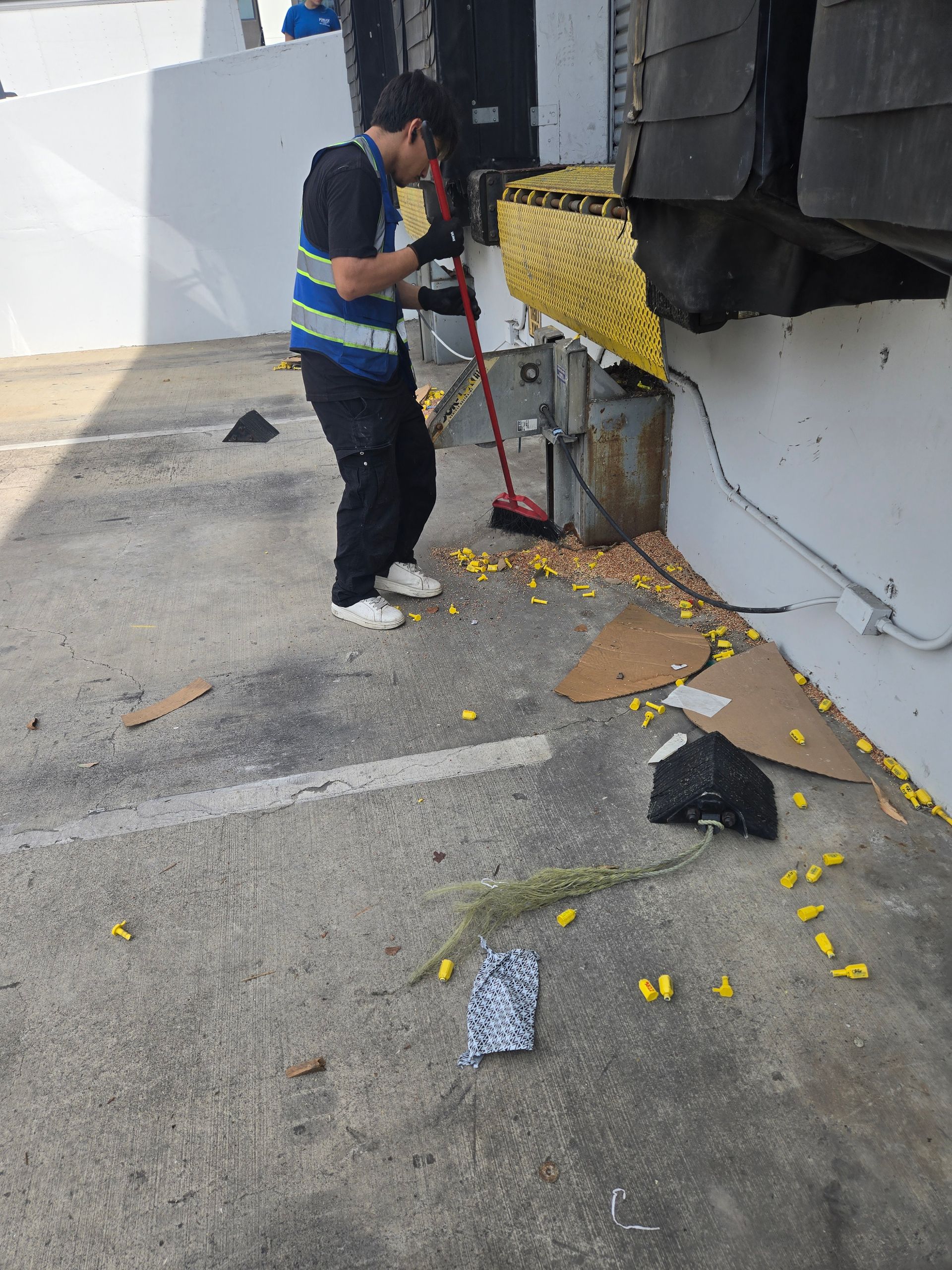 Person cleaning an office desk with spray bottle and cloth, wearing blue gloves.