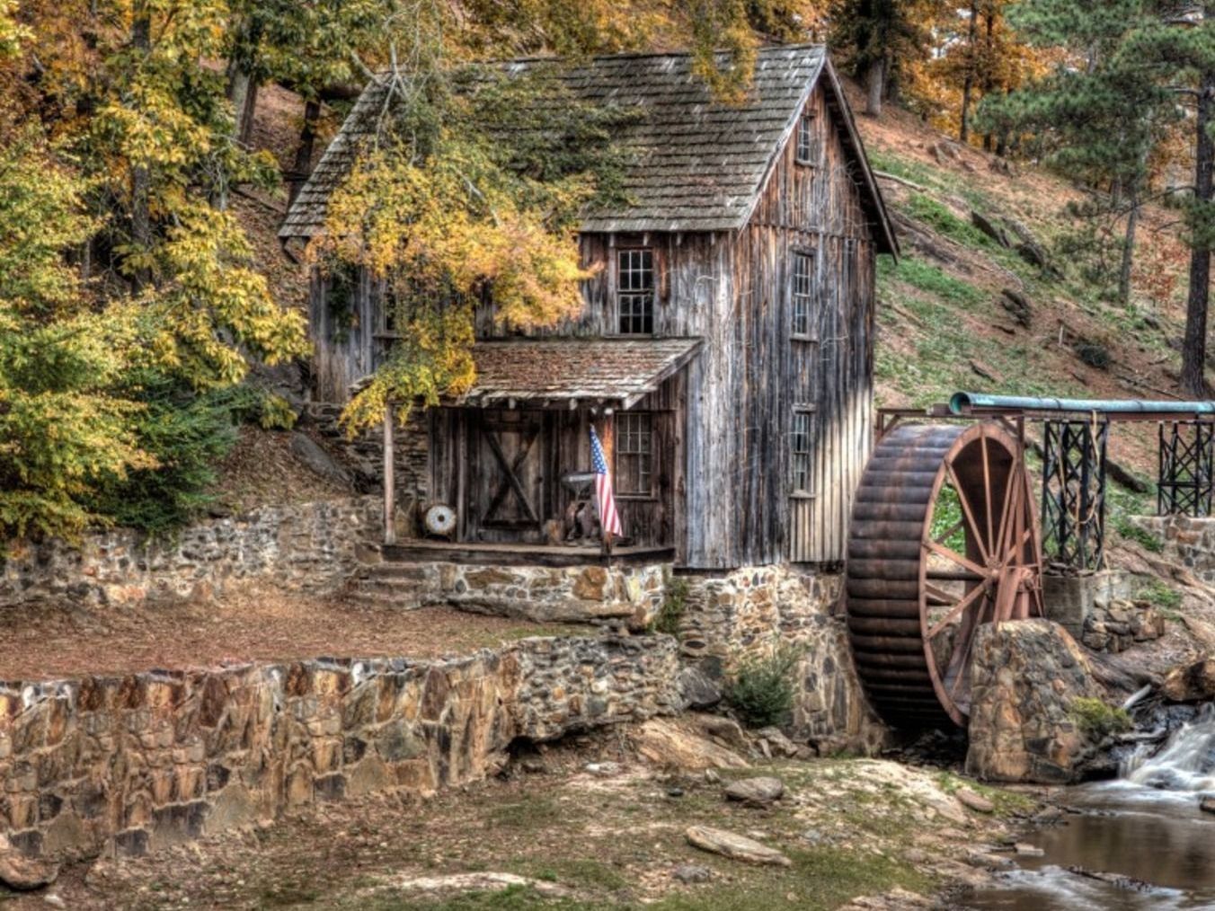 An old wooden house with a water wheel in front of it.