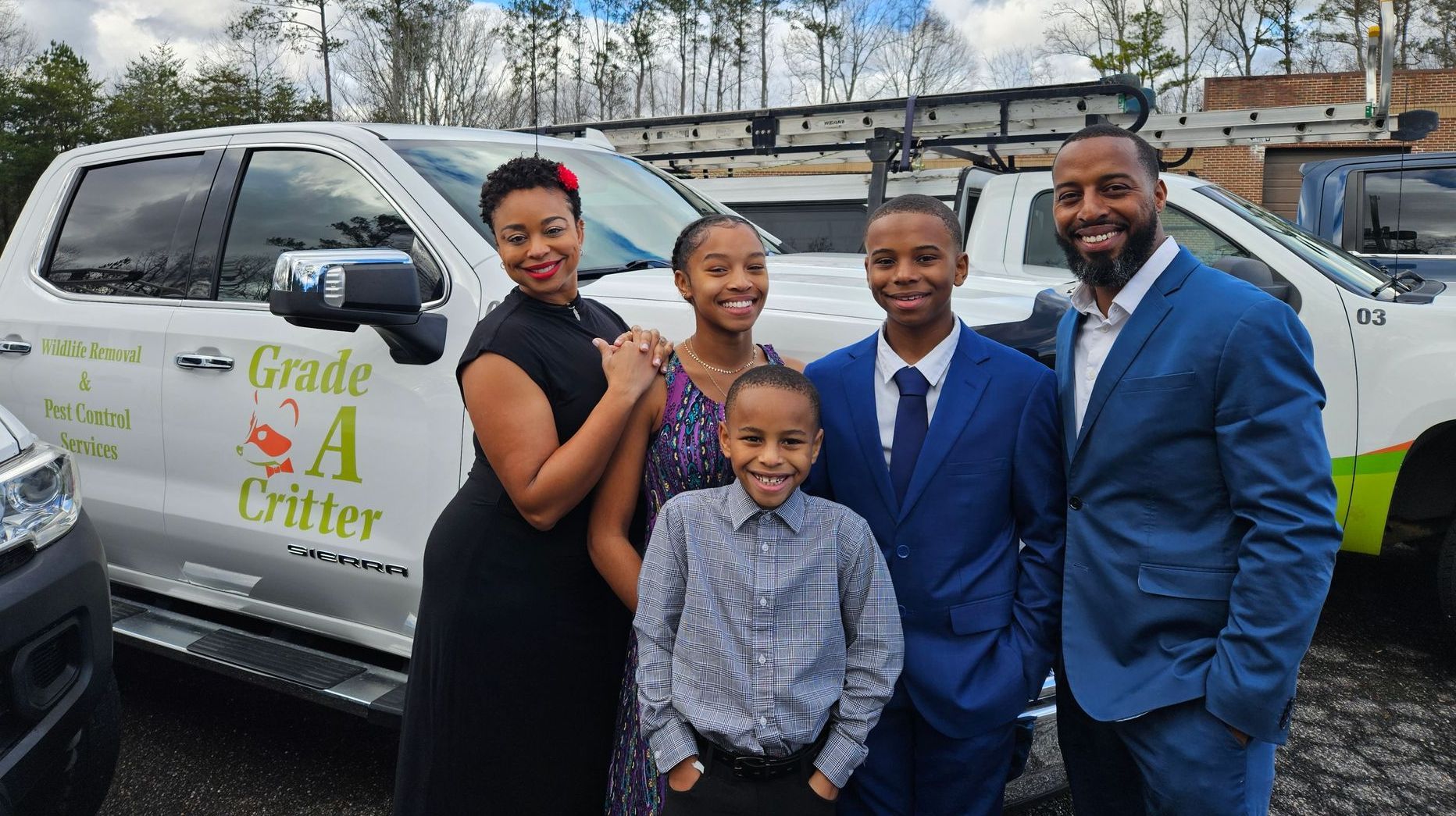 A family is posing for a picture in front of a truck.