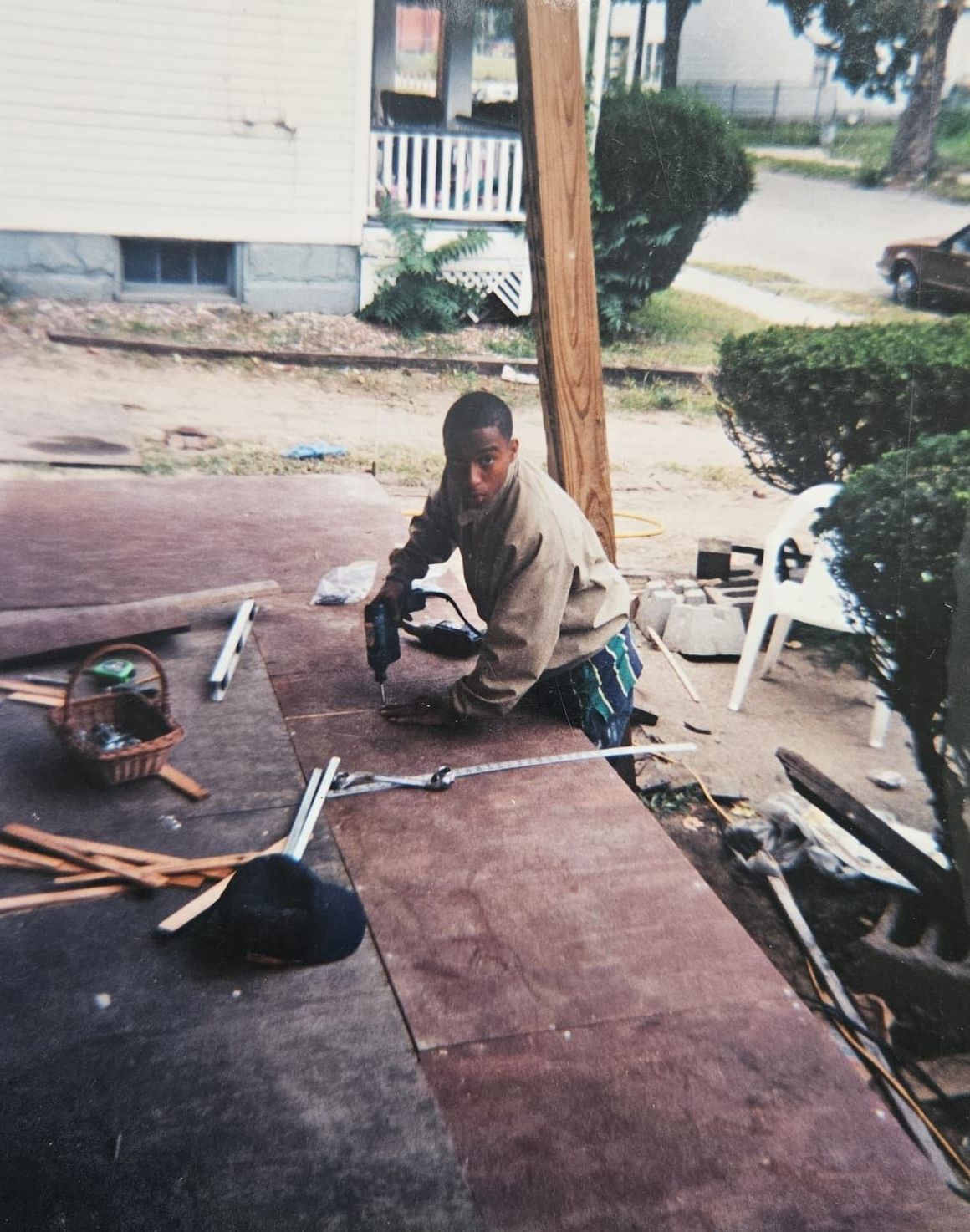 A man is kneeling down in front of a house working on a porch