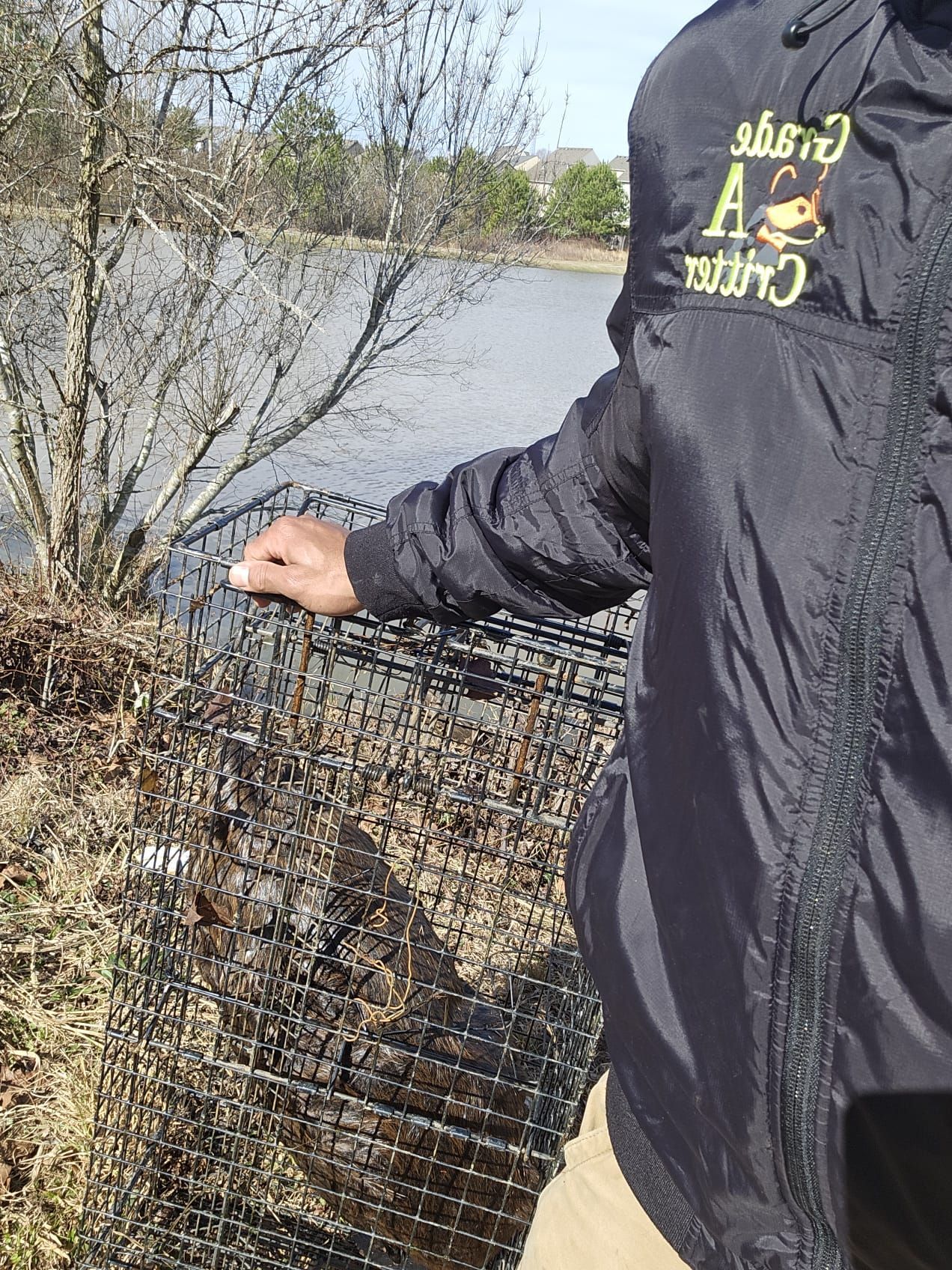 A person in a black jacket is standing next to a cage.