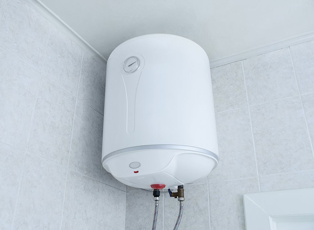 a white water heater is hanging from the ceiling in a bathroom .