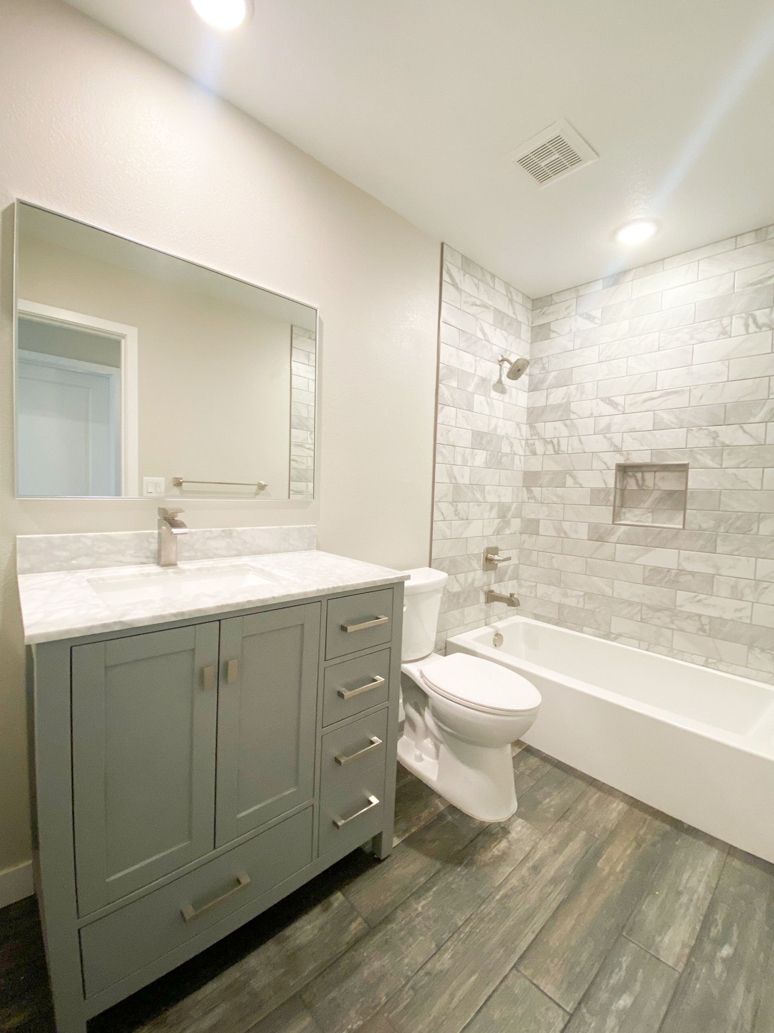 A bathroom with a toilet , sink , tub and mirror.