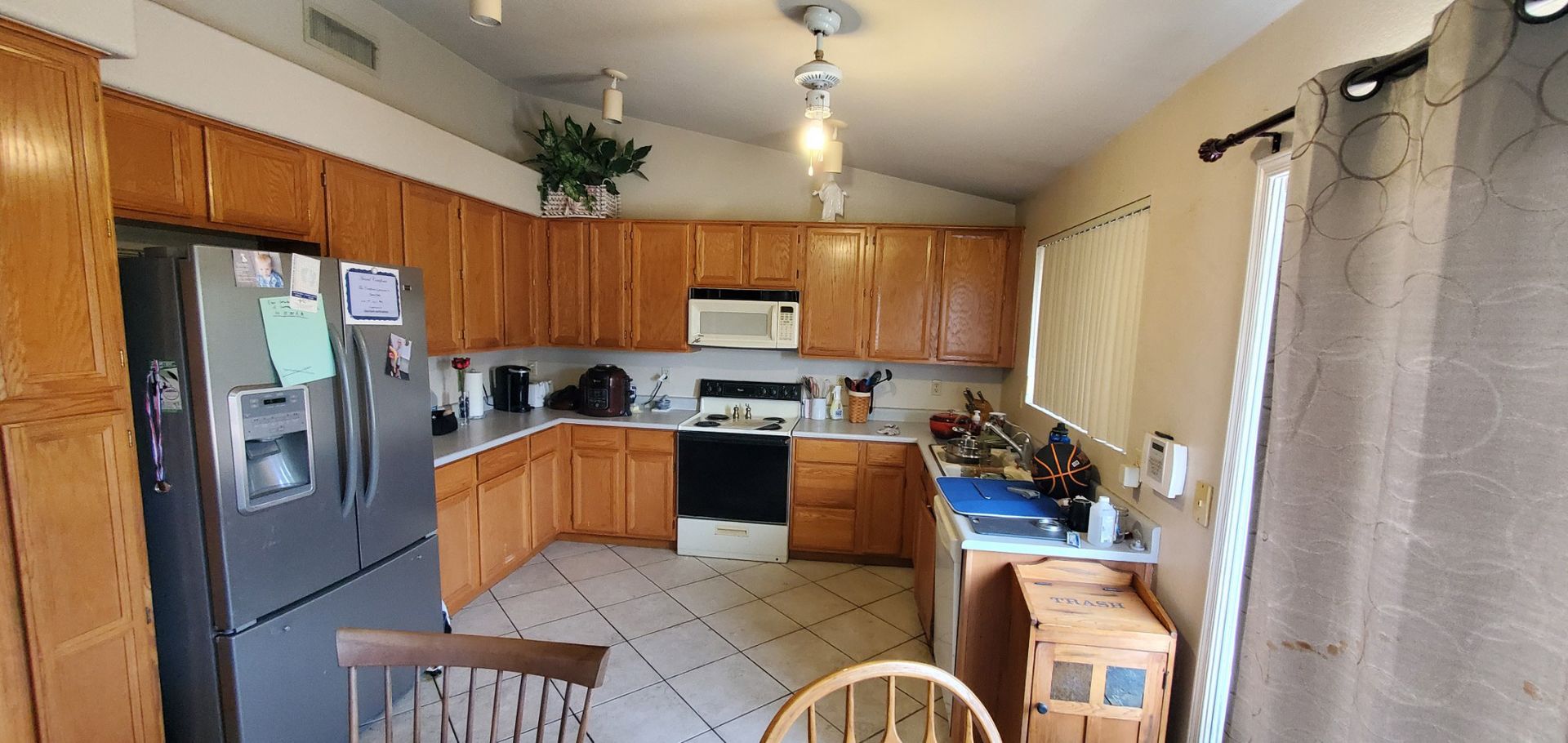 A kitchen with wooden cabinets , a stainless steel refrigerator , a microwave , and a stove.