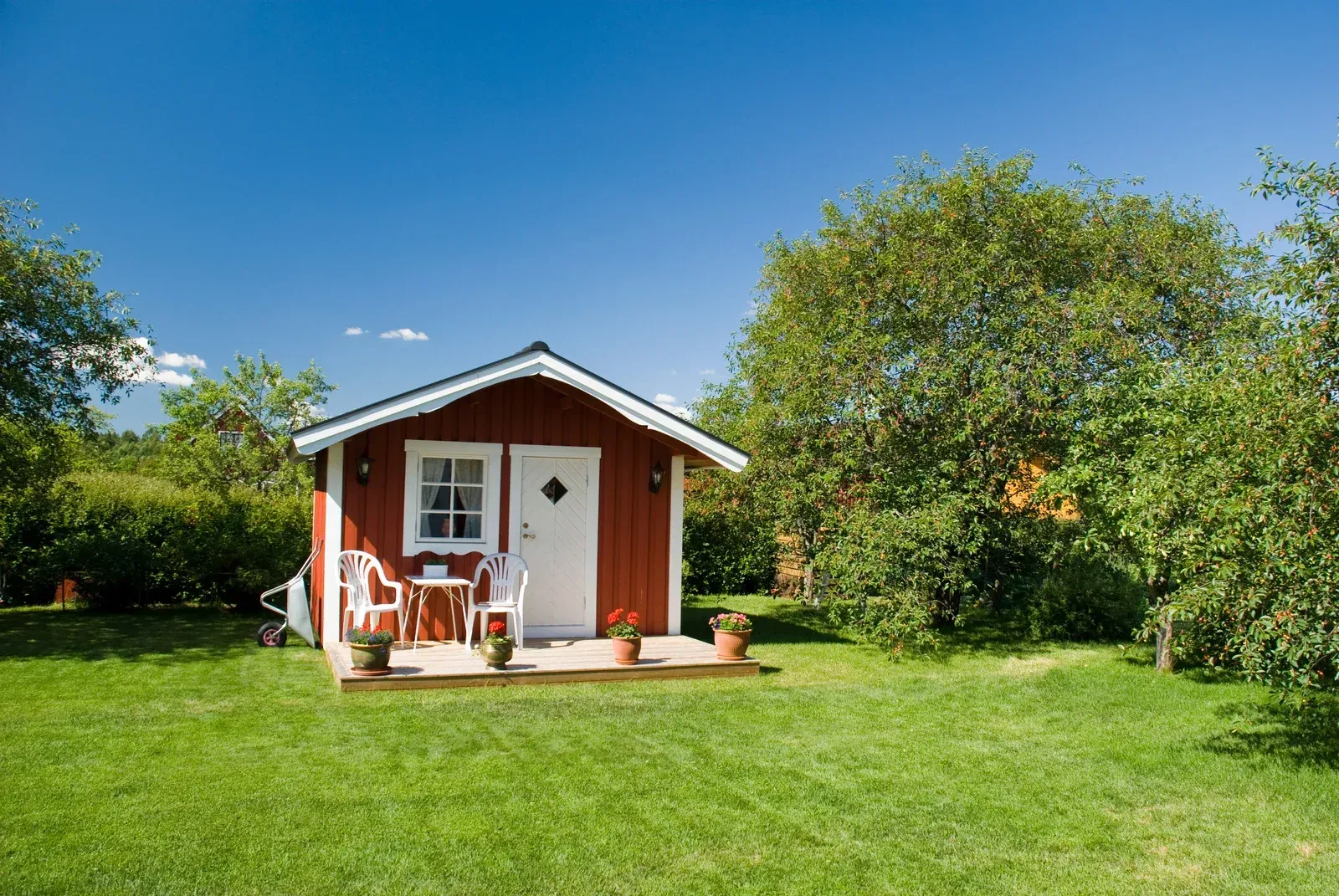 Modern house with pool; wooden deck, pergola, and square stepping stones on green grass, blue sky.
