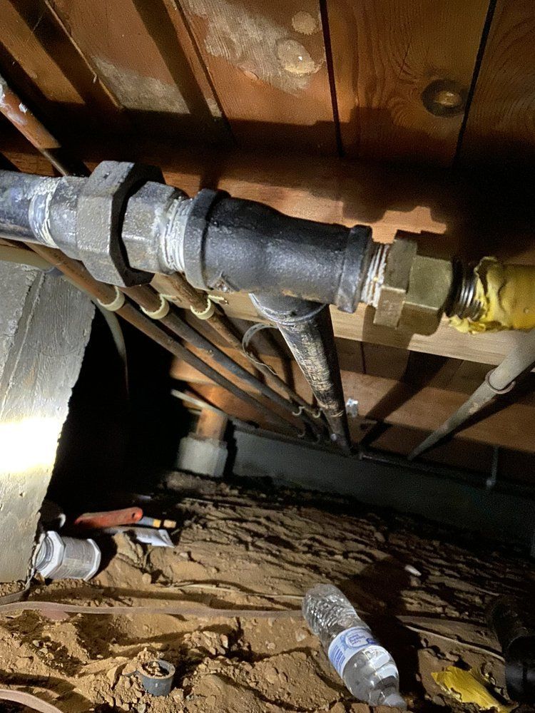 A bunch of pipes are hanging from the ceiling of a house.