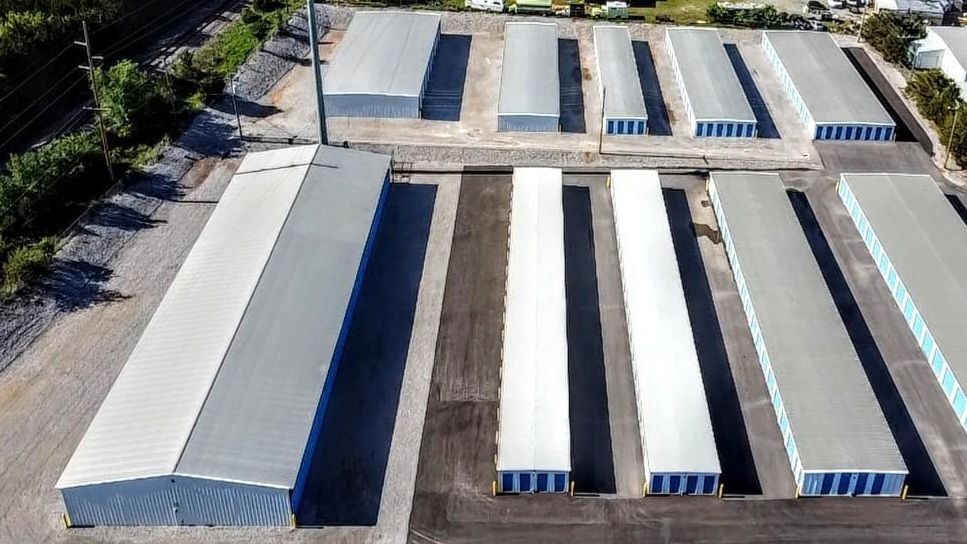 Boxes and a wrapped item on a blue cart in a storage unit hallway lined with red doors.